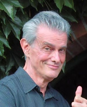 Ein Mann mit grauen Haaren und einem schwarzen Hemd.