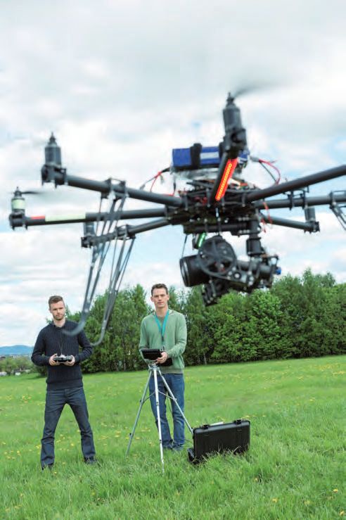 Zwei Männer stehen mit einer Drohne auf dem Feld.