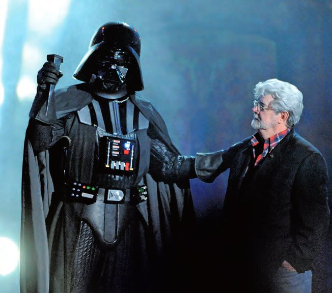 Ein Mann in einem Anzug, der neben einem Darth Vader-Kostüm steht.
