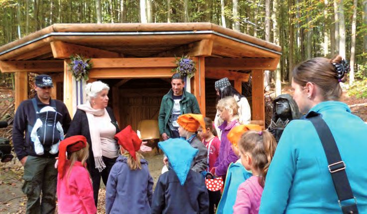 Eine Gruppe von Menschen, die um einen Holzbau stehen.