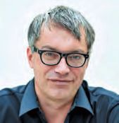 Ein Mann mit Brillen und einem blauen Hemd.