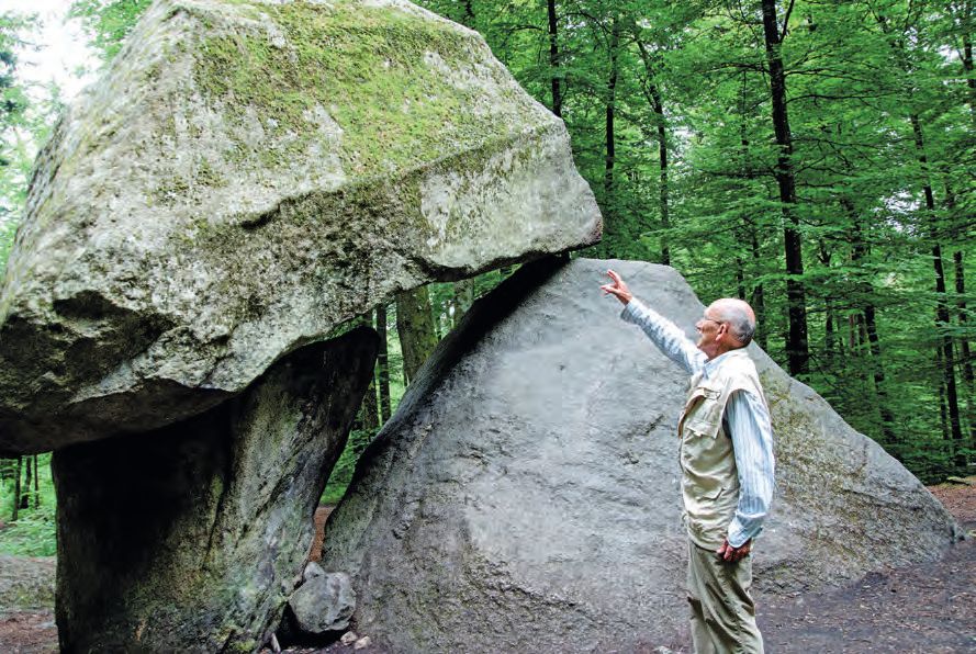 Ein Mann, der vor einem großen Felsen steht.