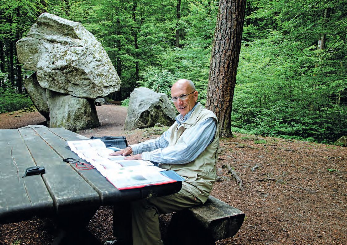 Ein Mann sitzt an einem Picknicktisch im Wald.
