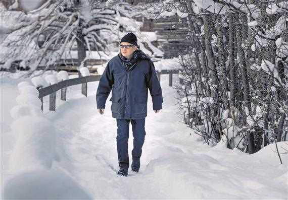 Ein Mann, der durch einen schneebedeckten Wald geht.