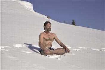 Ein Mann sitzt im Schnee auf einem Hügel.