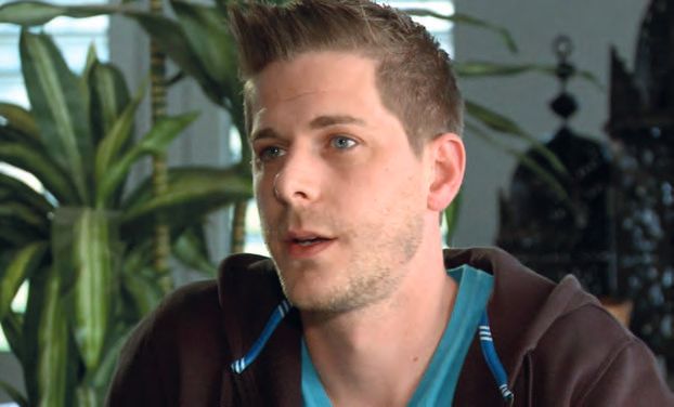 Ein Mann mit einem Mohawk, der vor einer Pflanze steht.