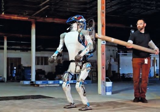 Ein Mann, der einen Stock neben einem Roboter hält.