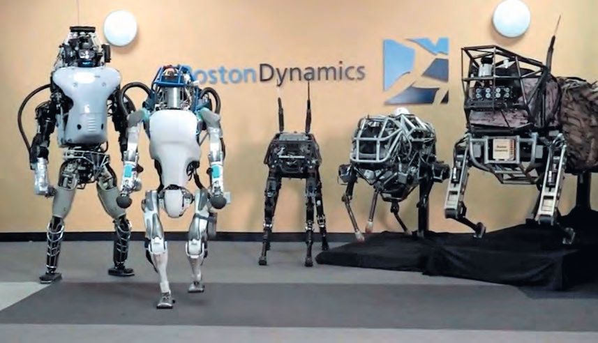 Eine Gruppe von Robotern, die vor einem Boston Dynamics-Schild stehen.