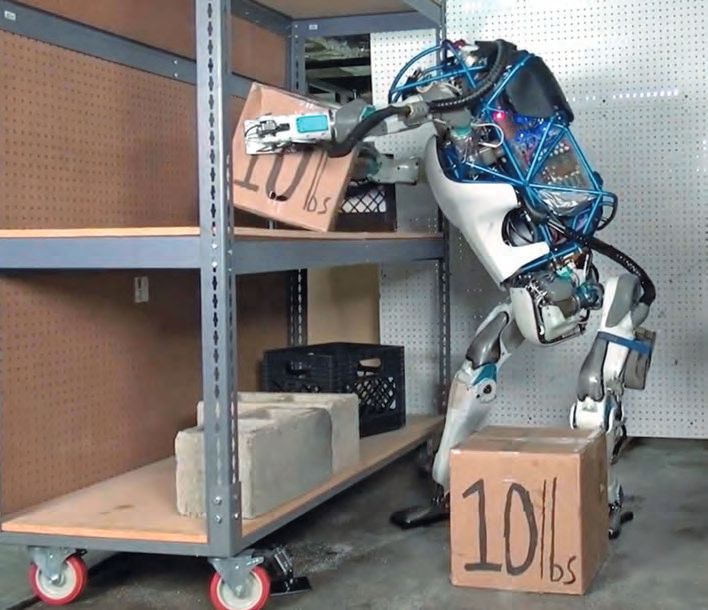 Ein Roboter steht neben einem Wagen mit Schachteln.