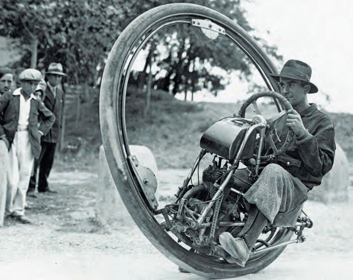 Ein Mann sitzt auf einem Motorrad mit einem riesigen Reifen.