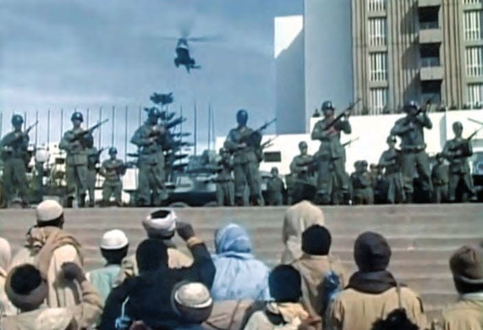 Eine Gruppe von Soldaten, die auf einer Bühne stehen, und über ihnen ein Hubschrauber fliegt.