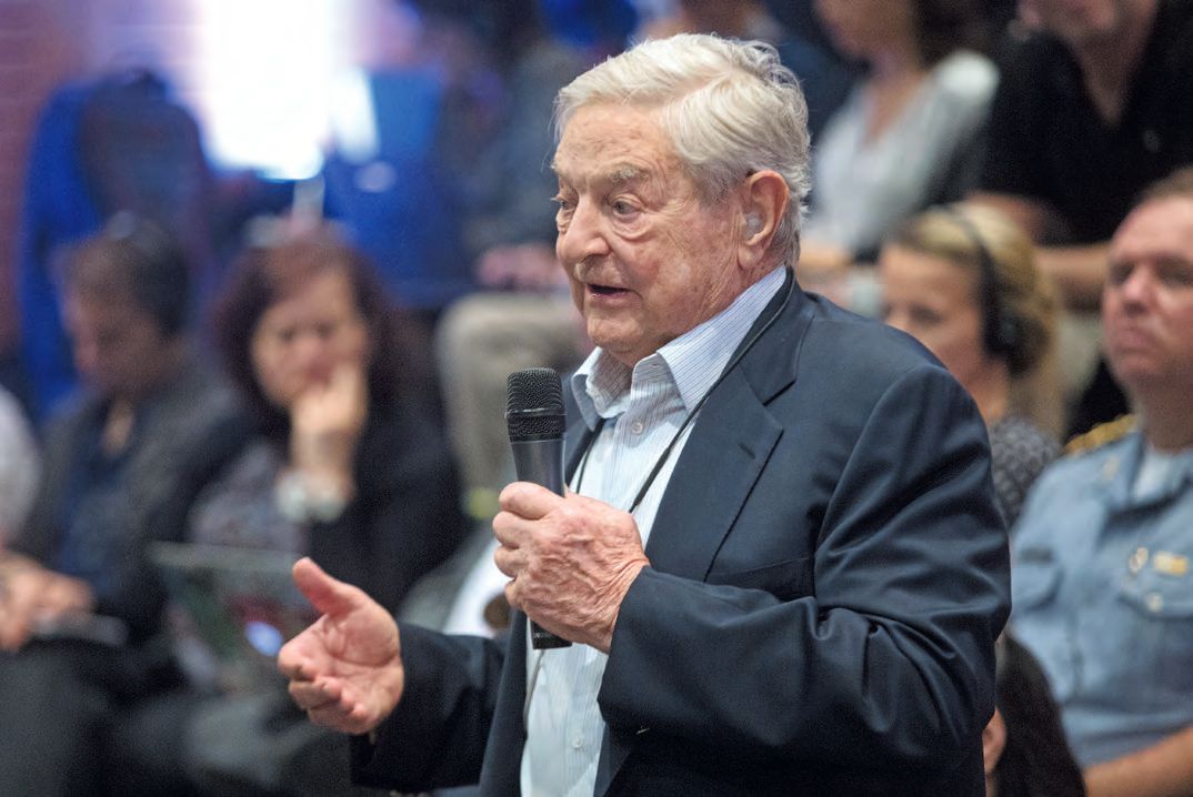 Ein Mann in Anzug und Krawatte und hält ein Mikrofon.