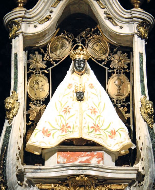 Eine Statue eines Mannes in einem weißen Mantel mit einer Krone oben.