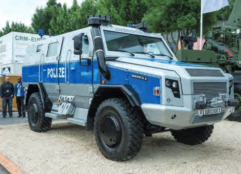 Ein großer blauer und grauer Lastwagen, der neben einem Militärfahrzeug geparkt ist.