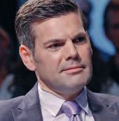 Ein Mann in Anzug und Krawatte schaut auf die Kamera.