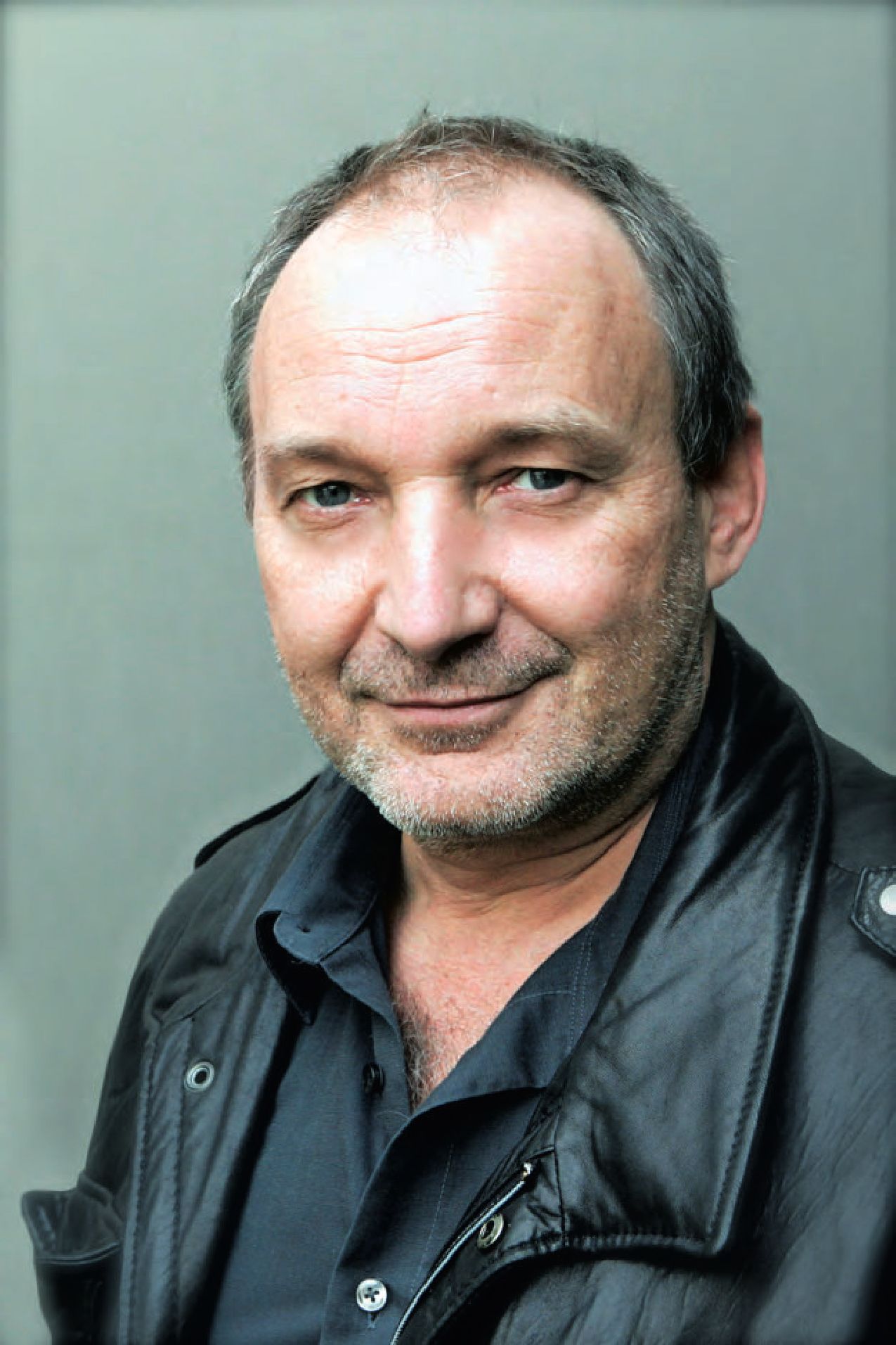 Ein Mann mit einem rasierten Kopf und einer schwarzen Jacke.