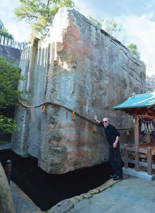 Ein Mann, der neben einem großen Felsen steht.