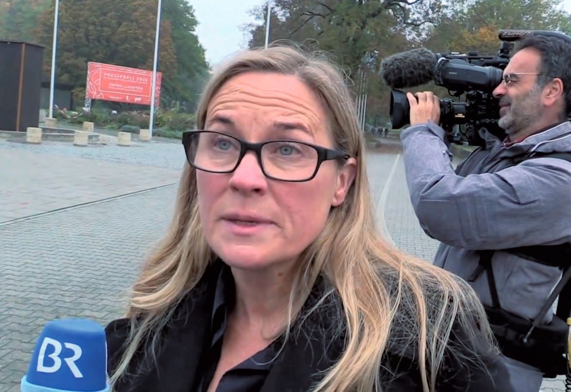 Eine Frau mit Brillen wird von einem Mann mit einer Kamera befragt.
