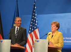 Ein Mann und eine Frau stehen auf einem Podium vor amerikanischen Flaggen.