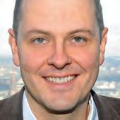 Ein Mann mit einem kahlen Kopf und einer Kostümjacke.