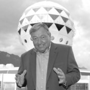 Ein Mann in einem Anzug steht vor einem riesigen Ball.