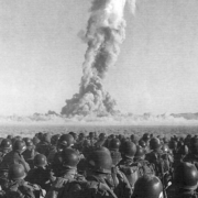 Eine große Gruppe von Soldaten steht auf einem Feld mit einer großen Rauchwolke hinter ihnen.