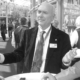 Ein Mann in Anzug und Krawatte steht vor einem Gebäude.