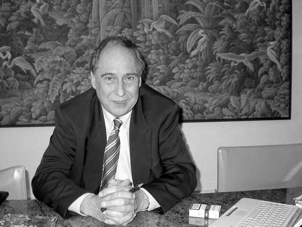 Ein Mann in einem Anzug sitzt an einem Schreibtisch mit einem Stift in der Hand.