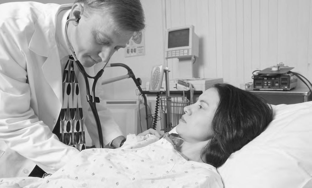 Ein Arzt, der einen Patienten in einem Krankenhausbett untersucht.